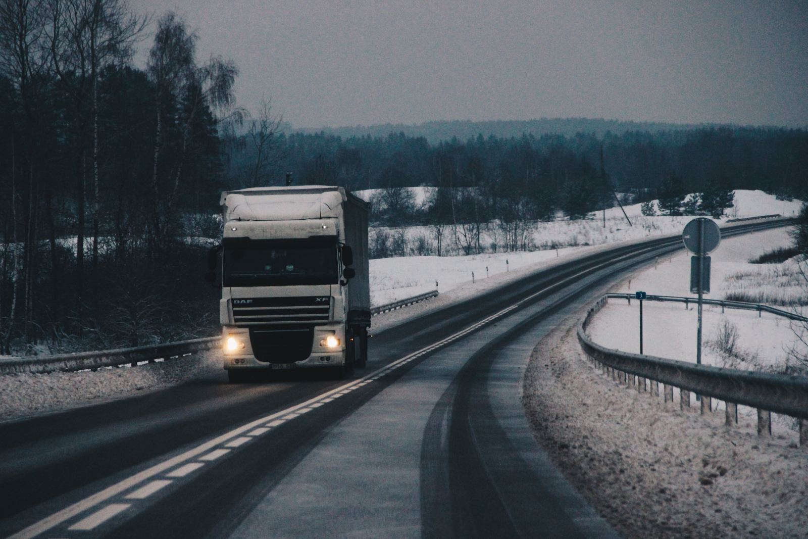 Truck driving down a snow-covered rural road