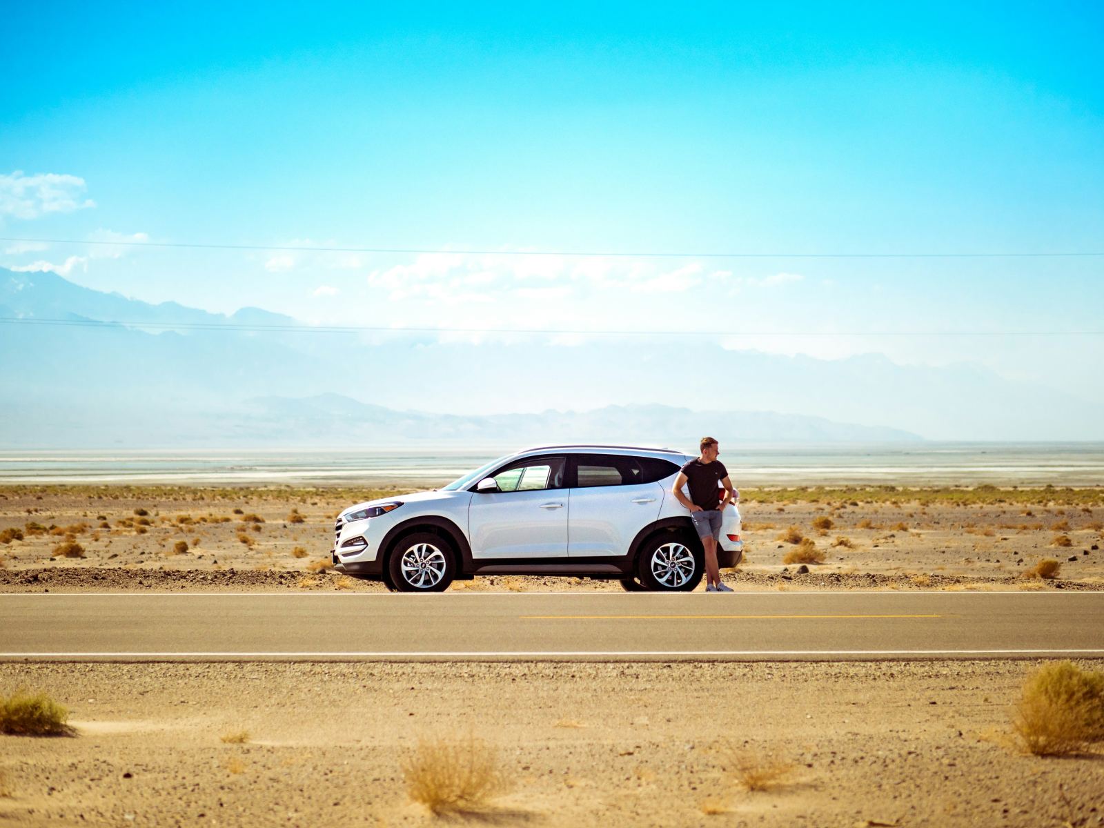 Man waiting beside his SUV parked on a remote desert road