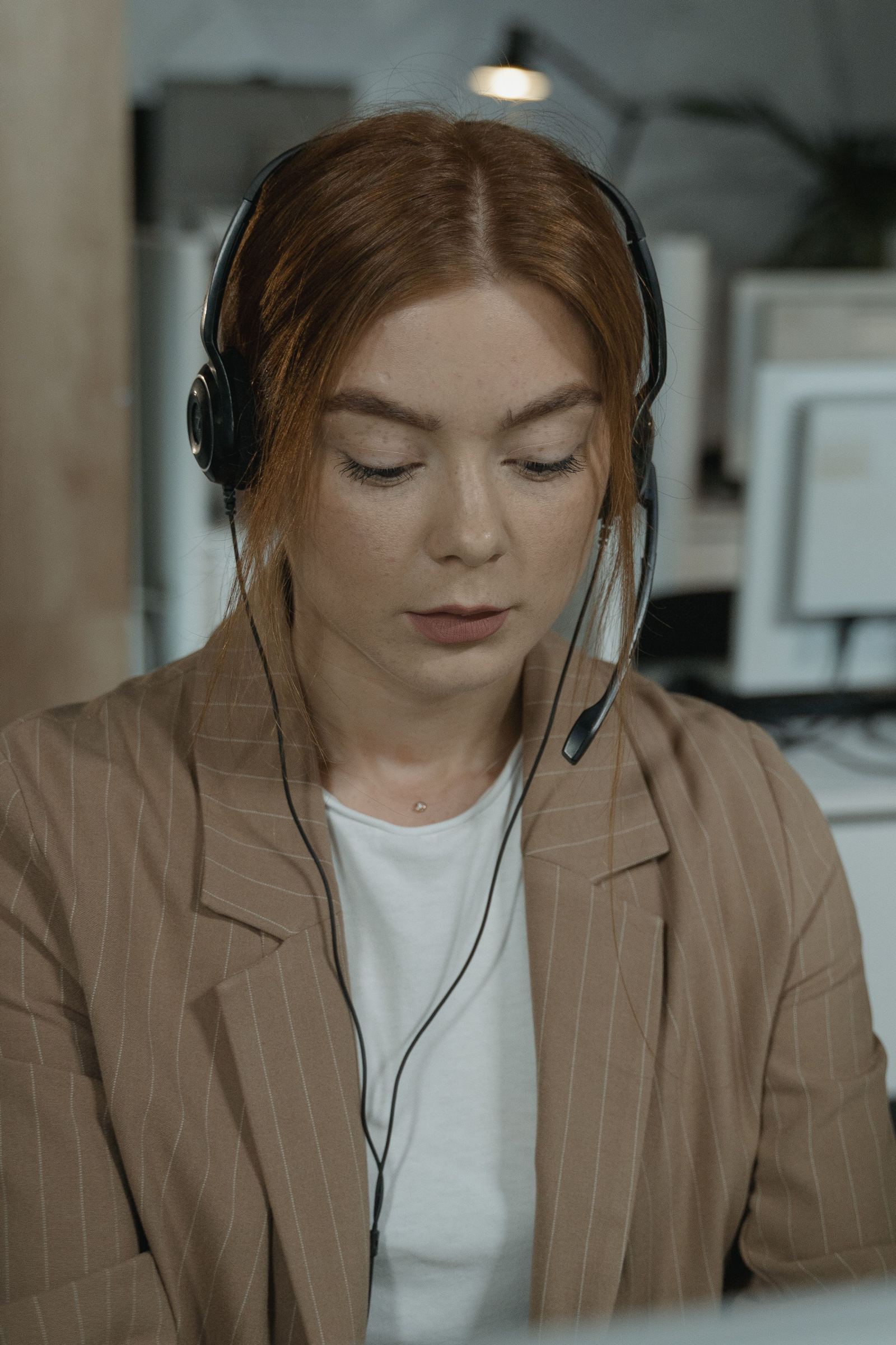 Dispatcher in a blazer wearing a headset while working at her desk