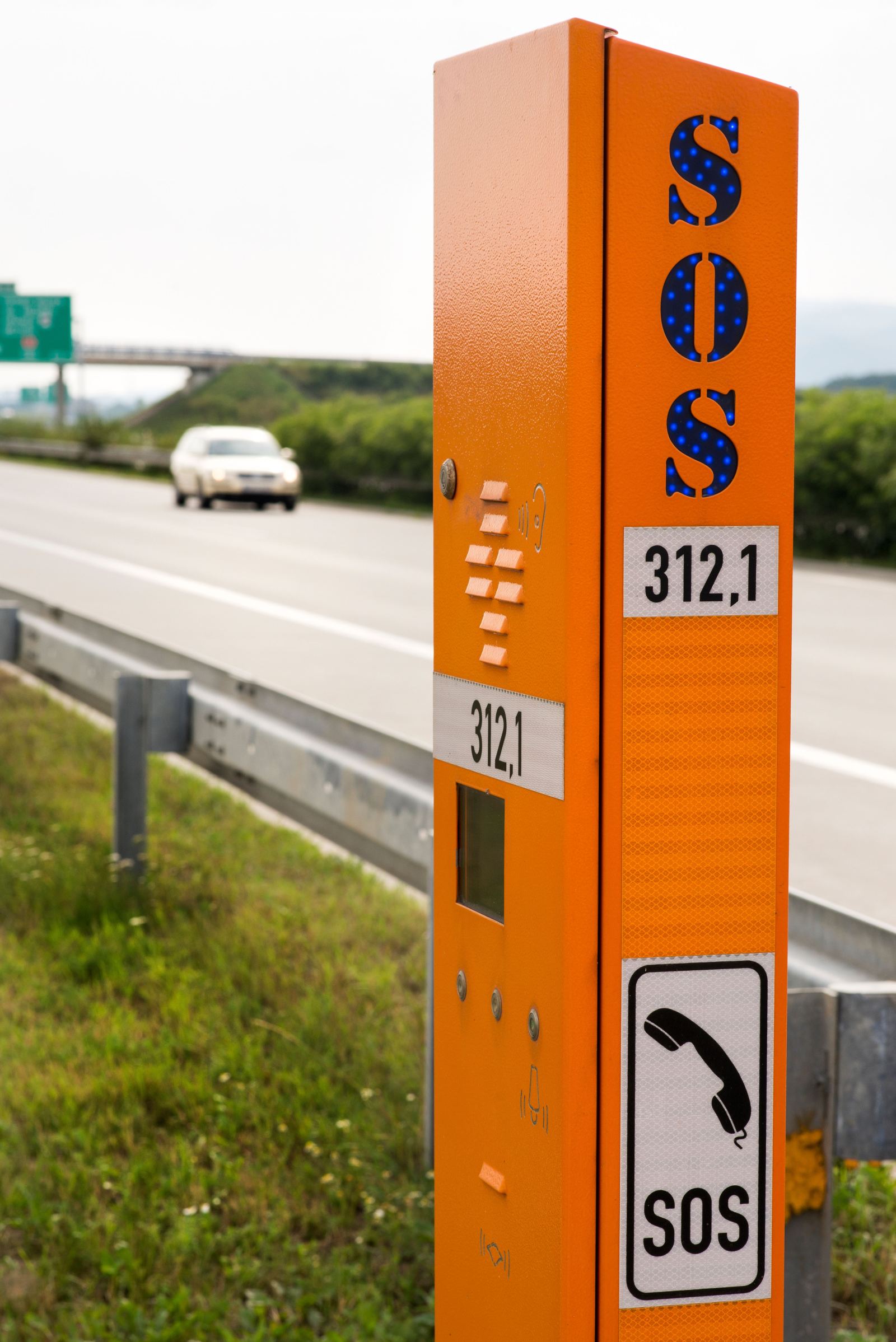 Orange emergency SOS call box on the shoulder of a highway