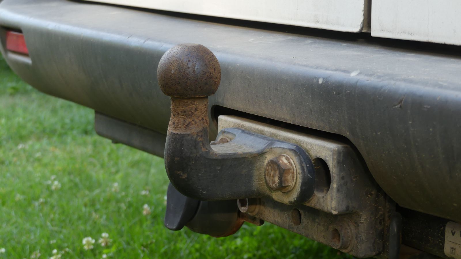 Close-up of a trailer hitch ball mount on a vehicle bumper