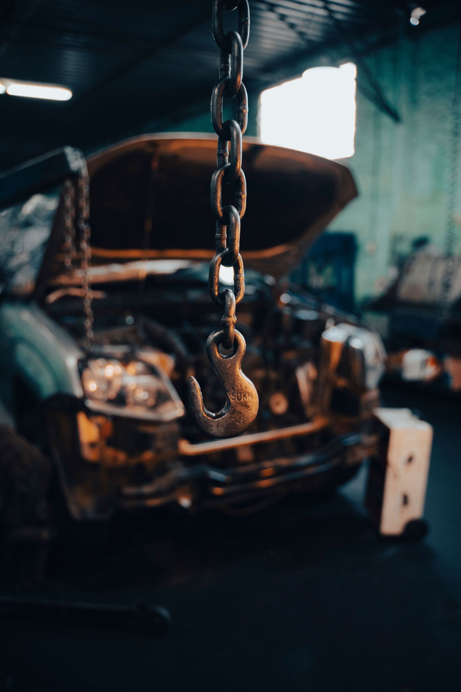 Close-up of a heavy-duty tow hook and chain hanging in a repair shop
