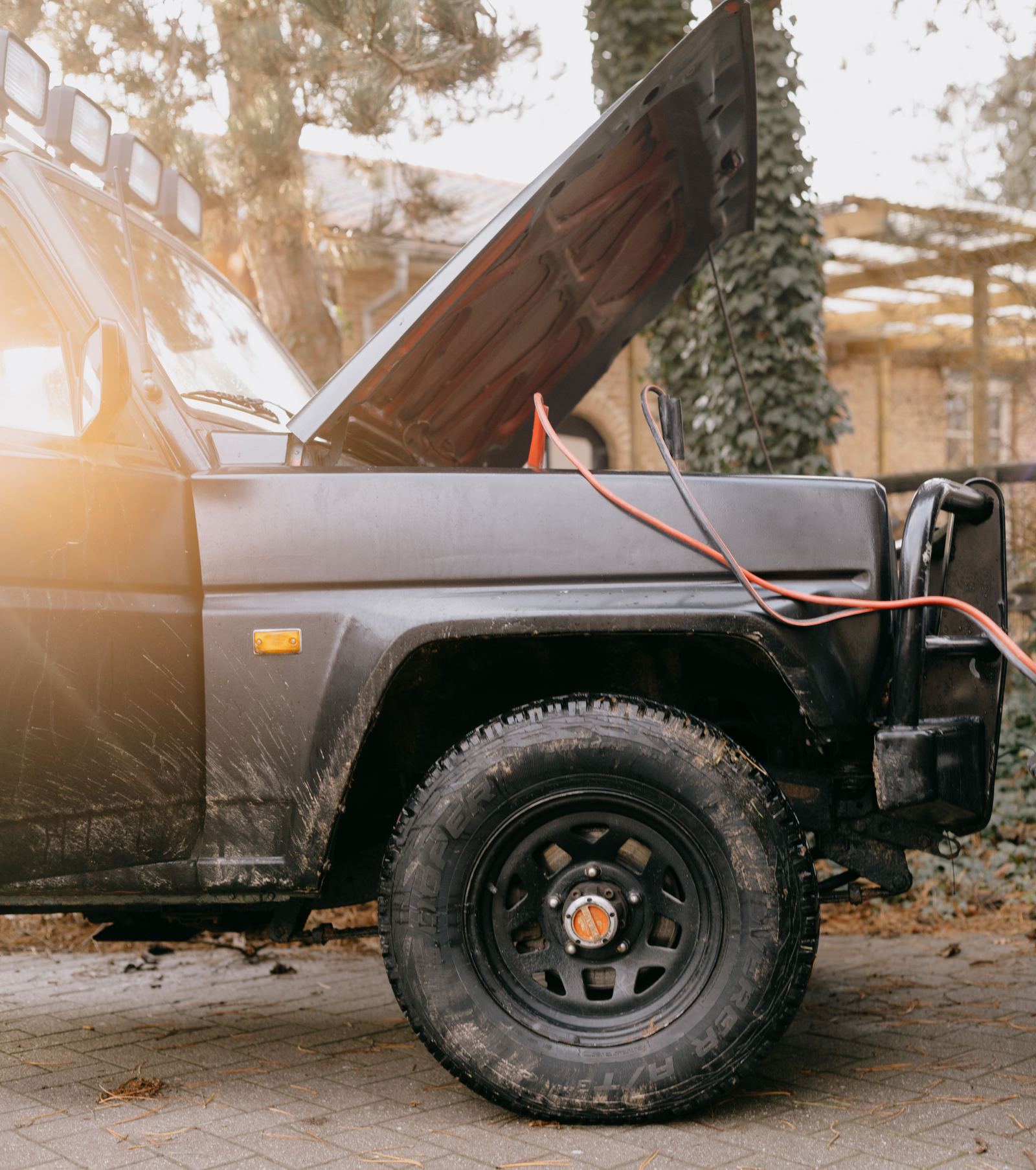 Jumper cables connected to the battery of an off-road vehicle with the hood open