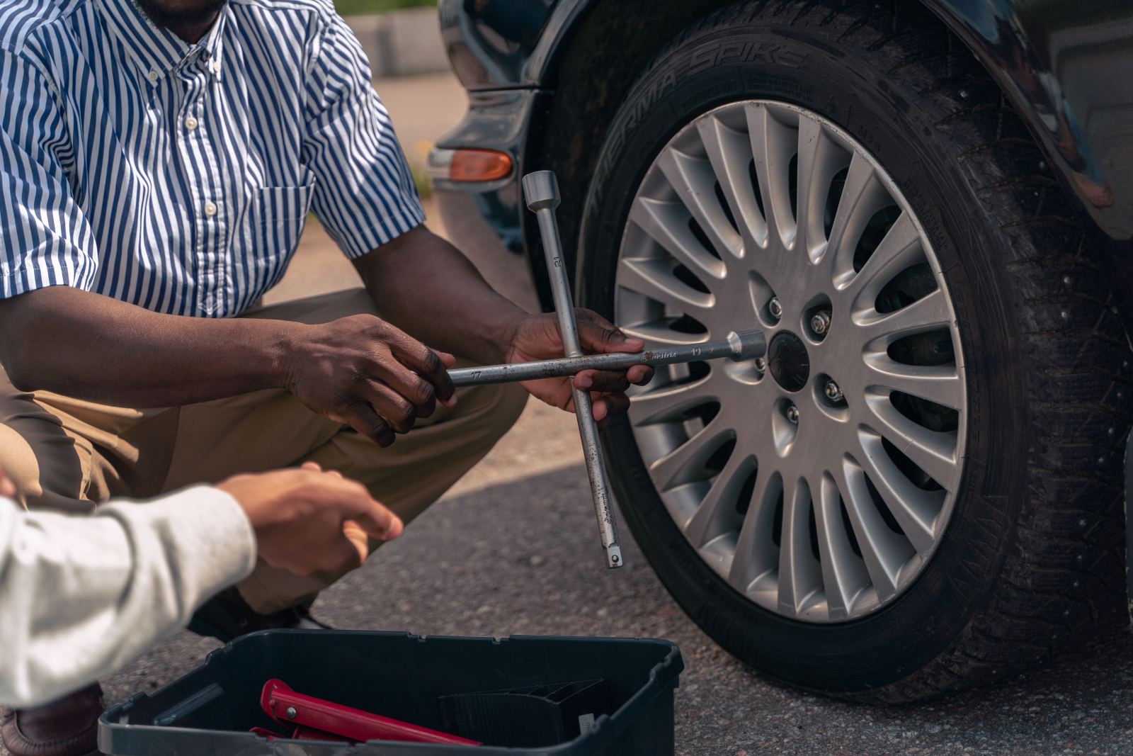 Close-up of hands using a lug wrench on a car wheel