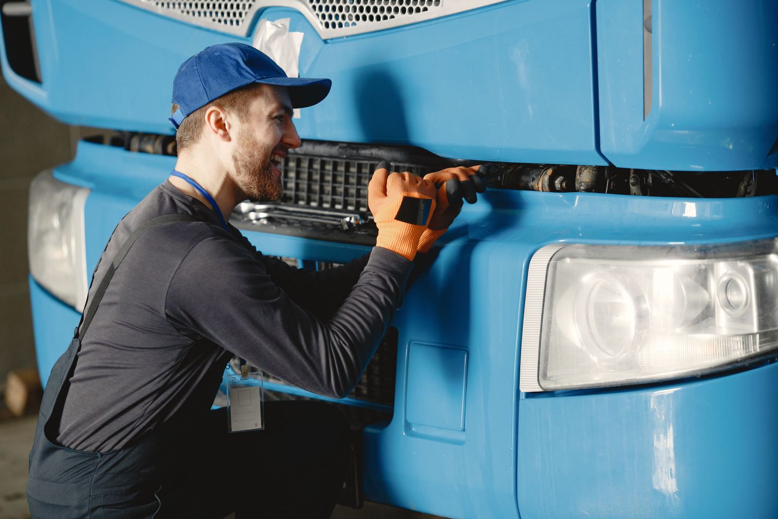 Mechanic smiling while repairing the front of a blue truck
