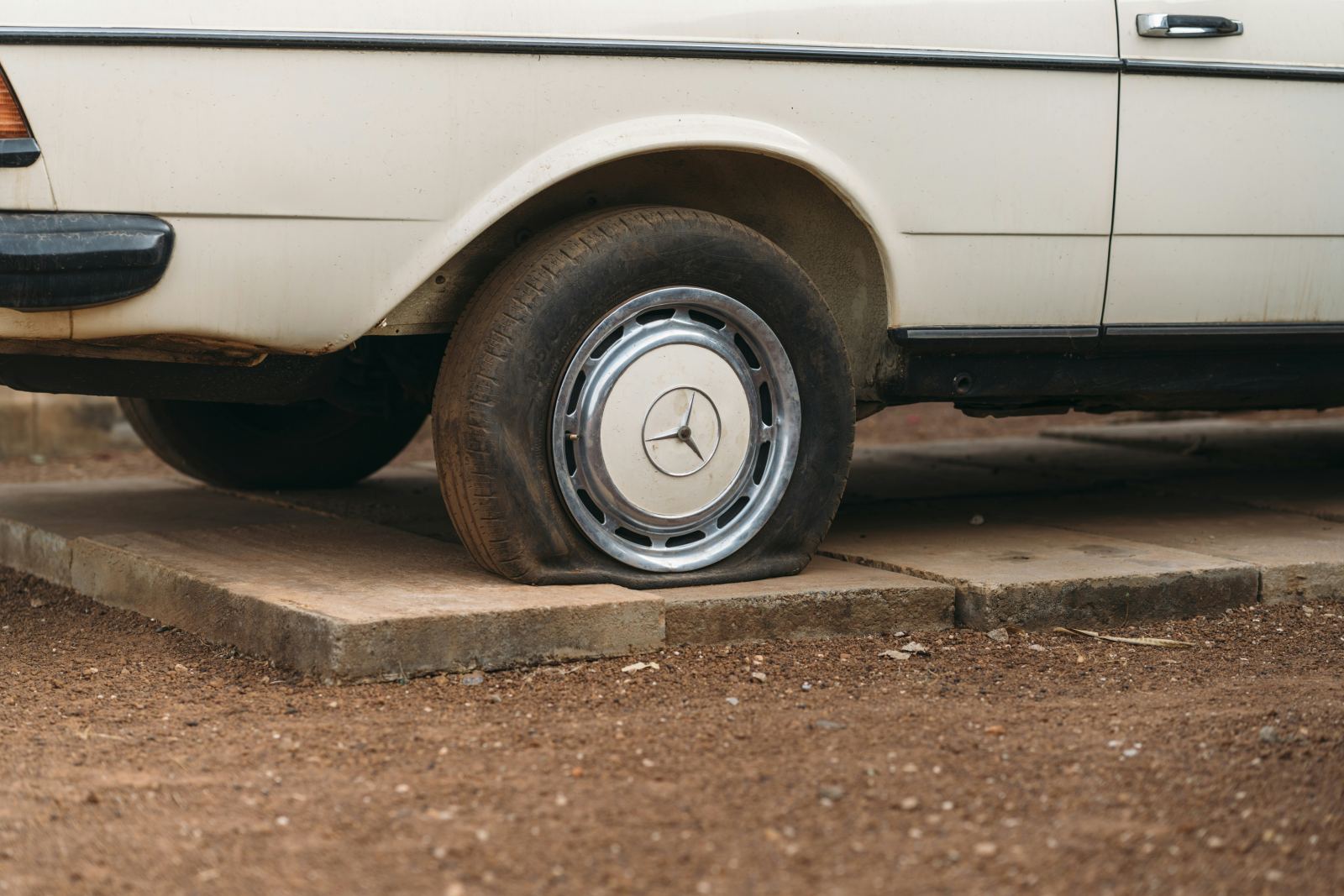 Close-up of a flat tire on a parked sedan