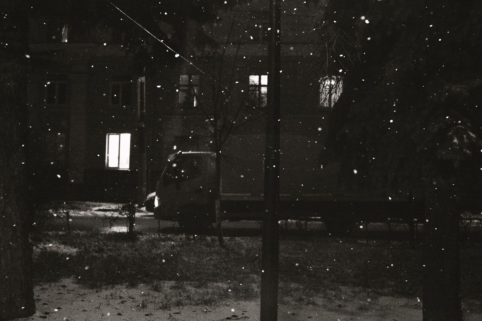 Van parked outside an apartment building during a night snowfall