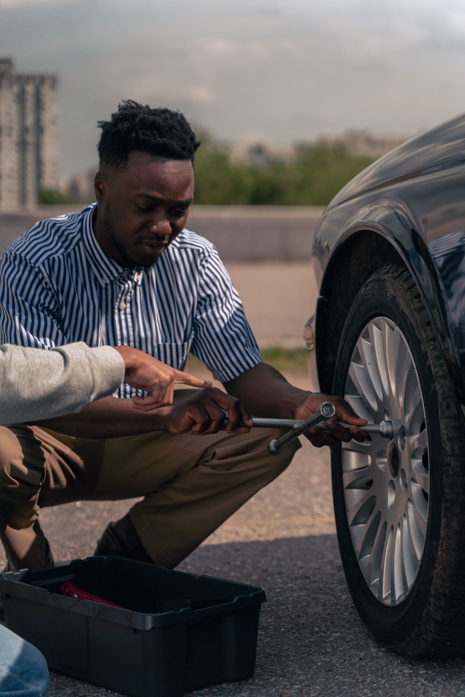 Two men working together to change a car tire with a lug wrench