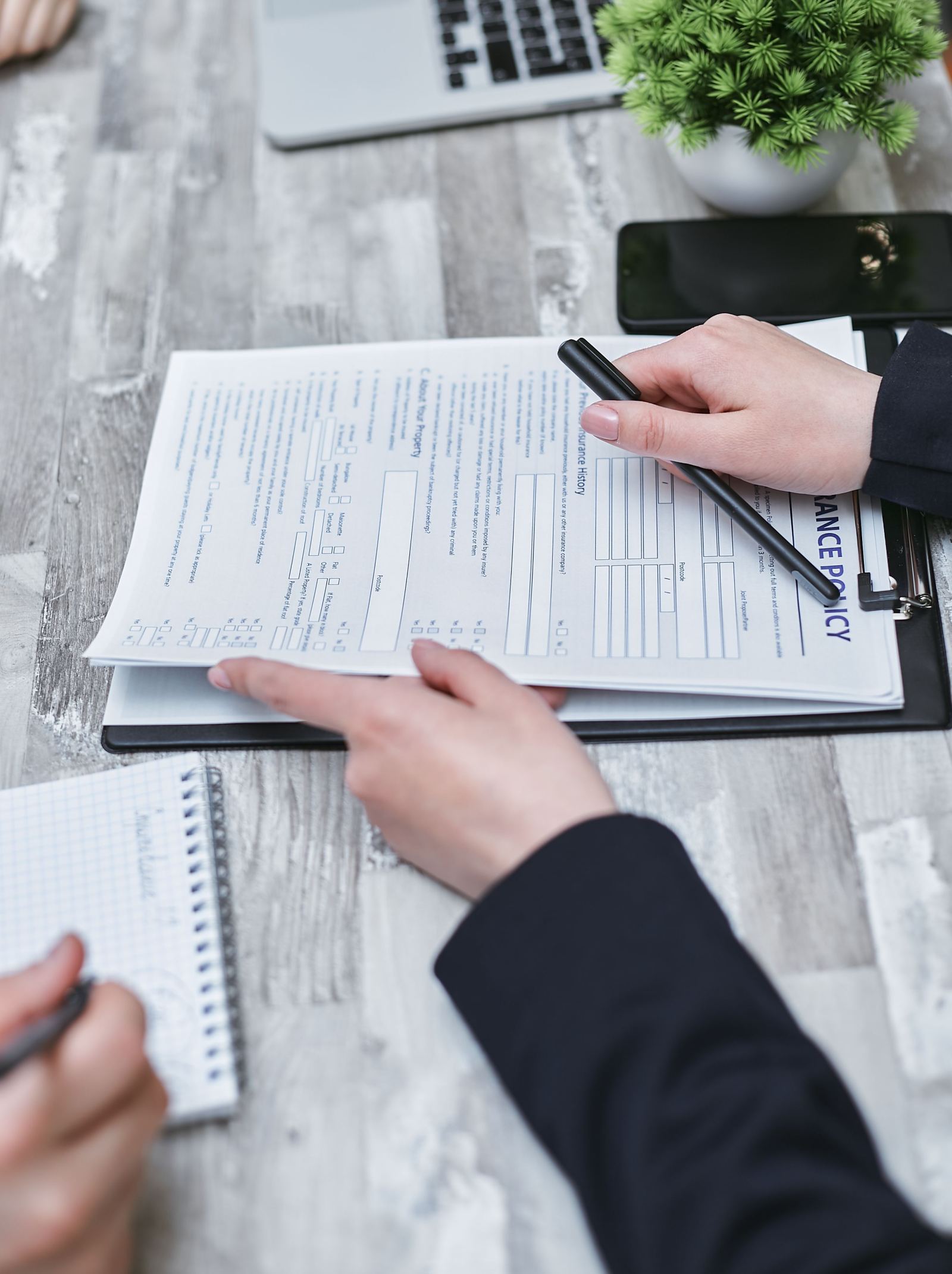 Hands reviewing insurance and compliance paperwork on a clipboard at a desk