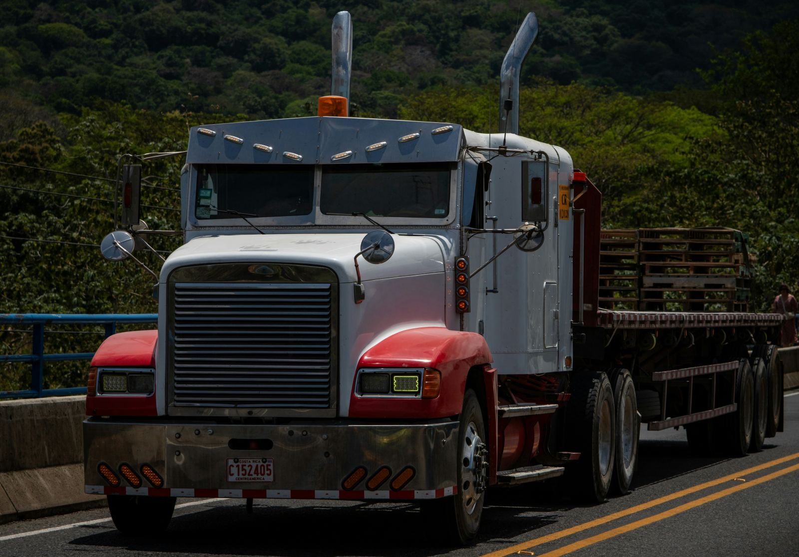 Semi truck with a flatbed trailer parked on a mountain road
