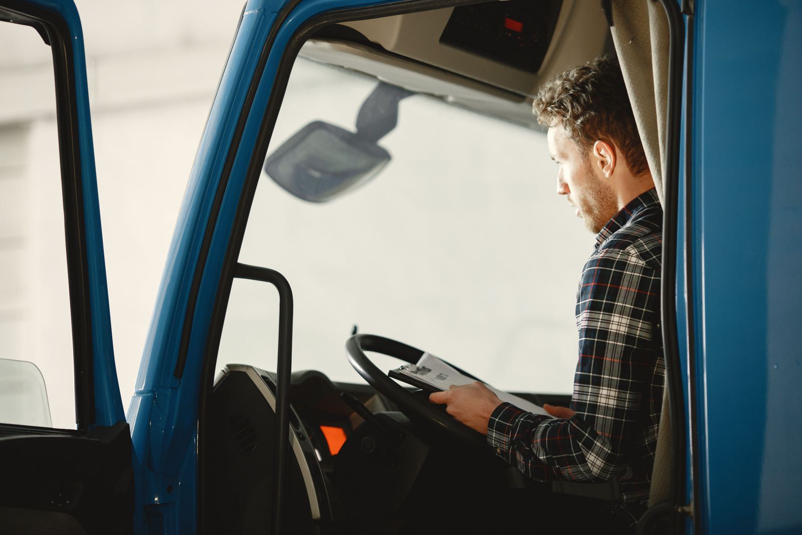 Truck driver reviewing a clipboard of paperwork while seated in the cab