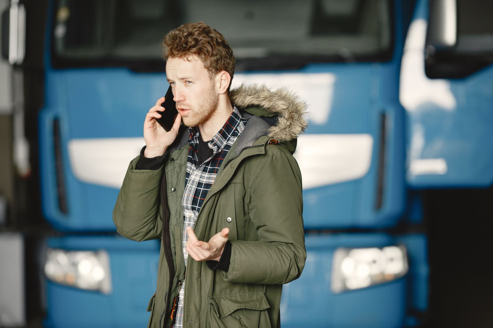 Man on a phone call standing in front of a blue truck cab