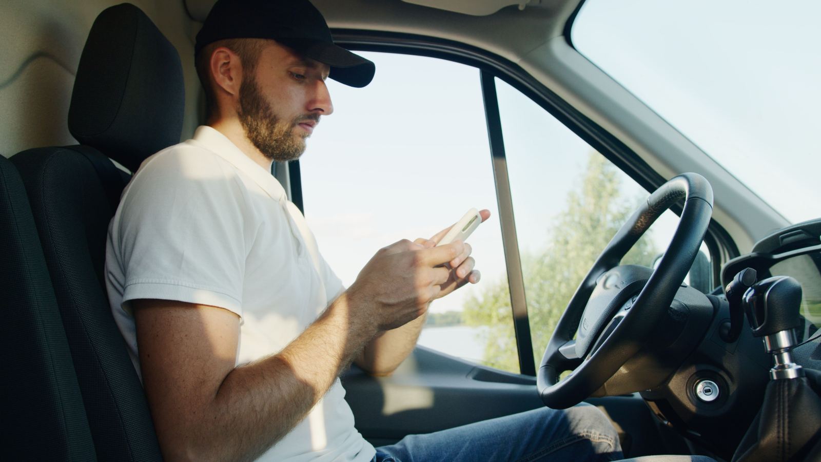 Truck driver checking his phone while seated behind the wheel
