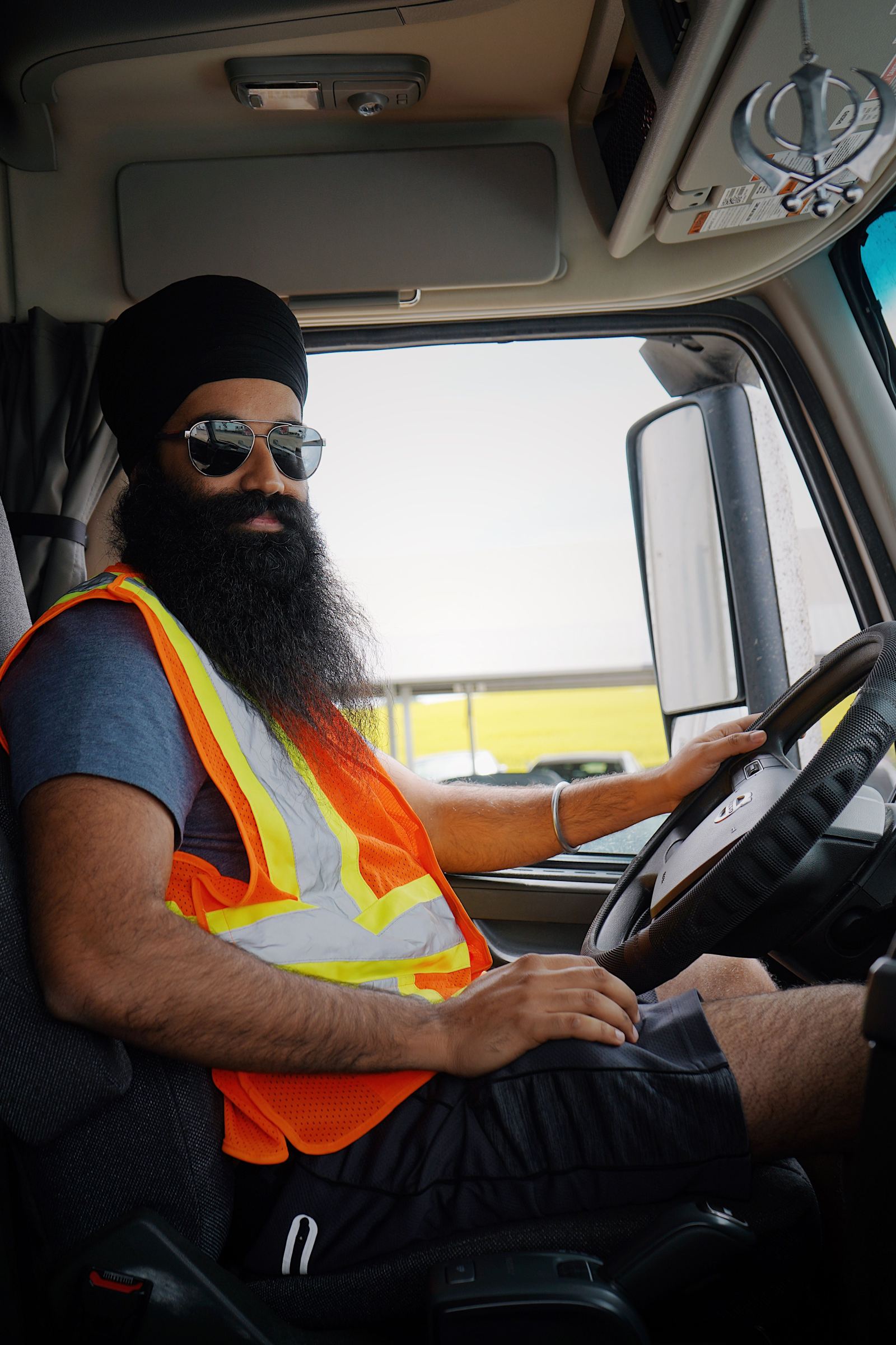 Truck driver wearing a turban and safety vest seated behind the wheel