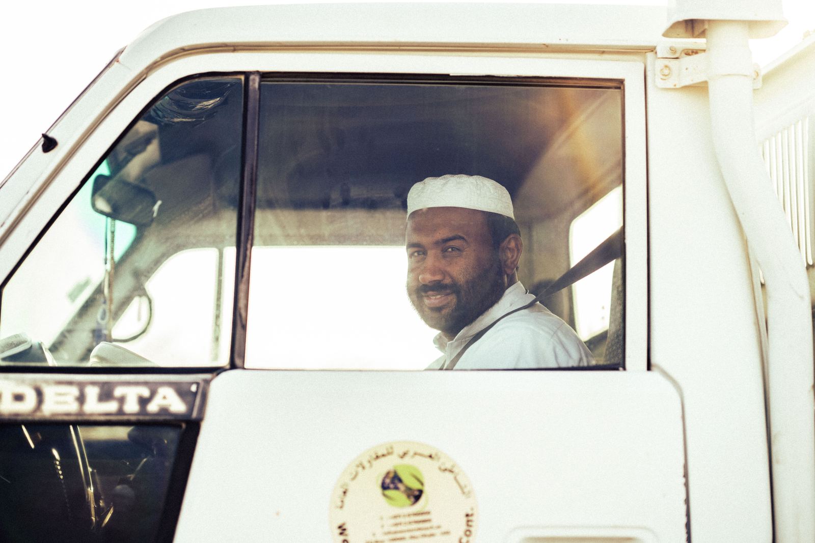 Truck driver smiling while seated in the cab looking out the window
