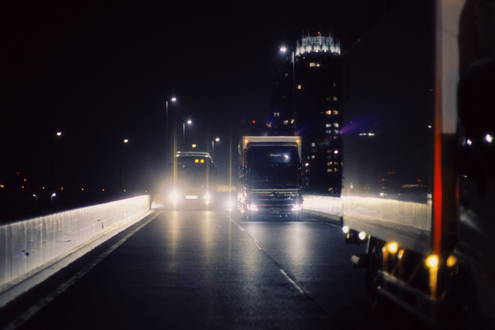 Semi truck driving through a city at night with an illuminated skyline behind it