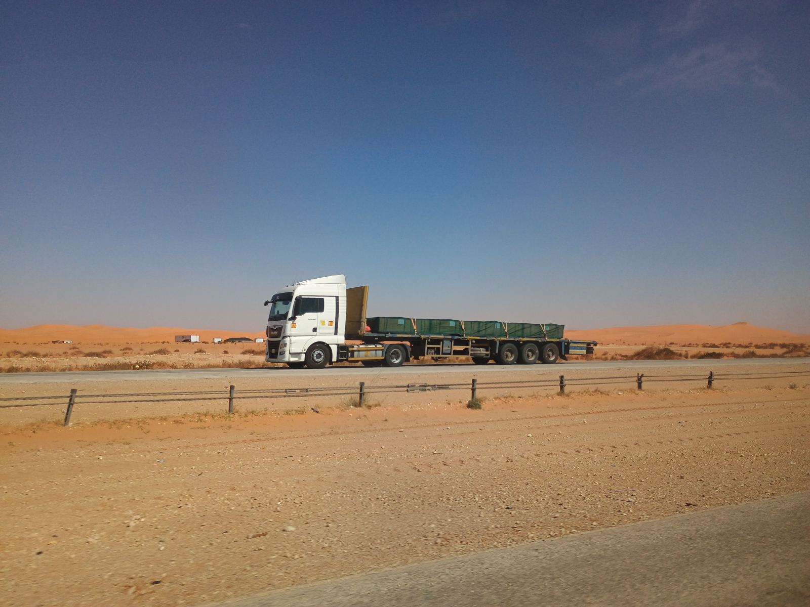 Flatbed truck hauling a covered load on a desert highway