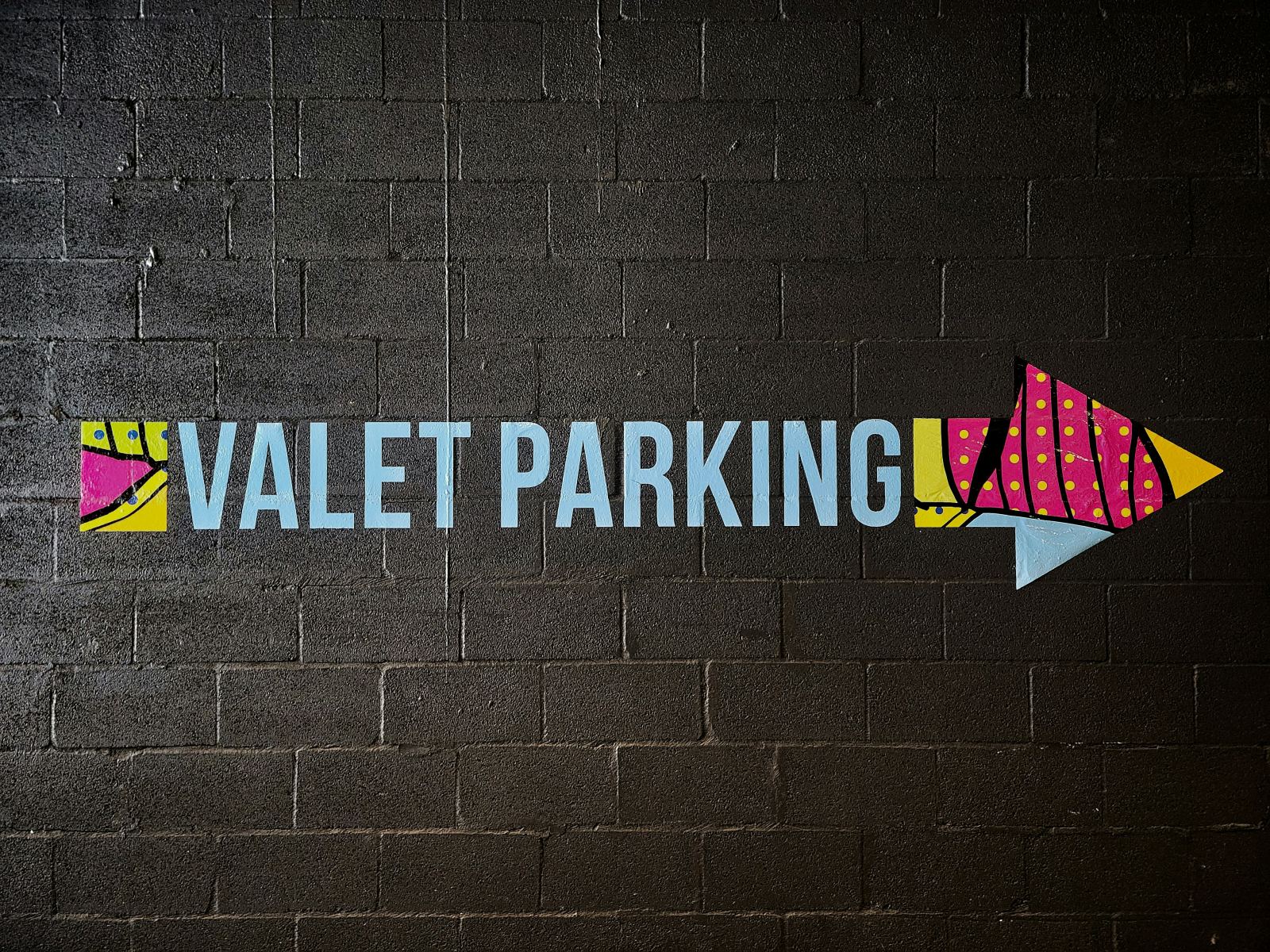 Hand-painted VALET PARKING sign with an arrow on a brick wall