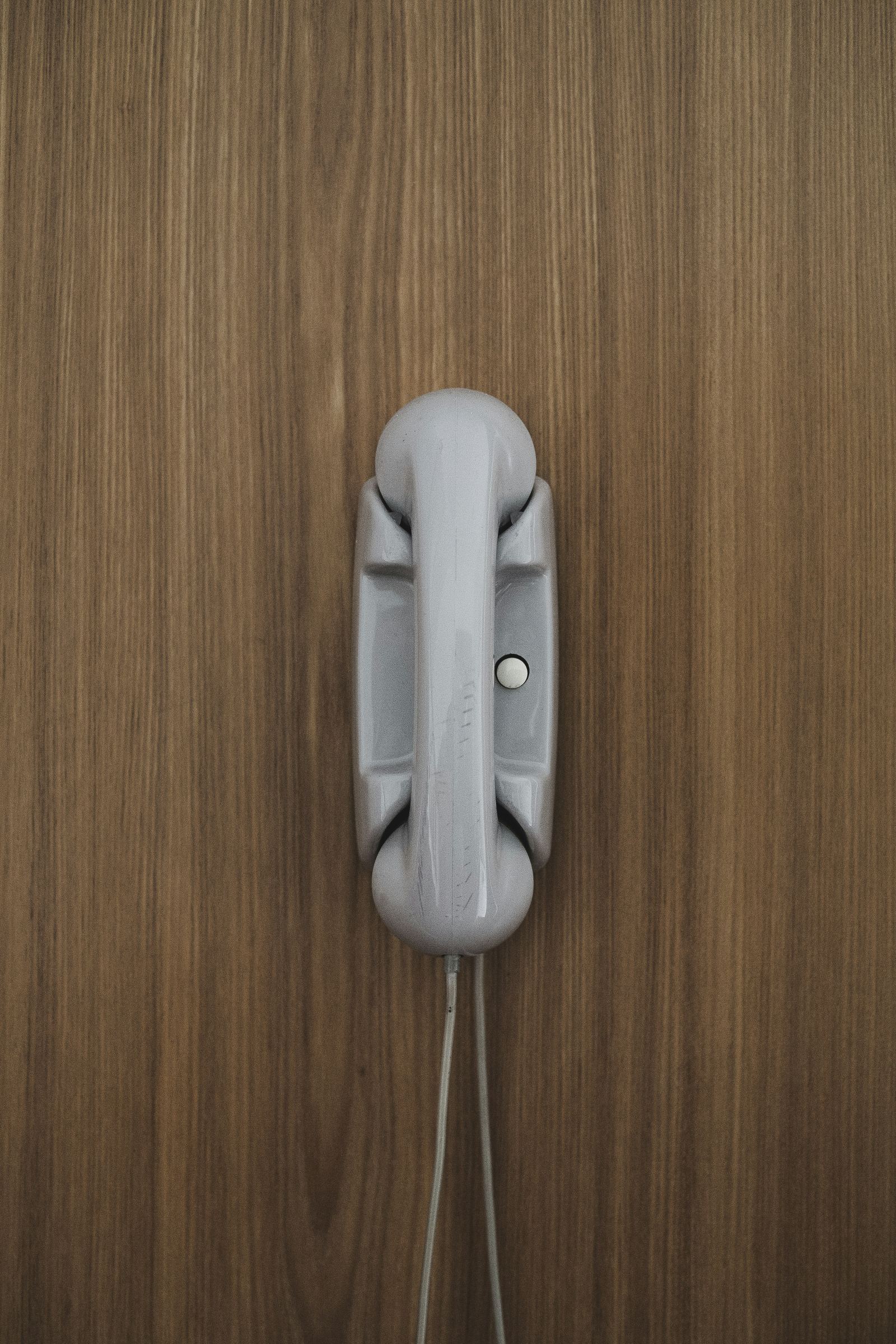 Vintage wall-mounted telephone handset on a wood-paneled wall