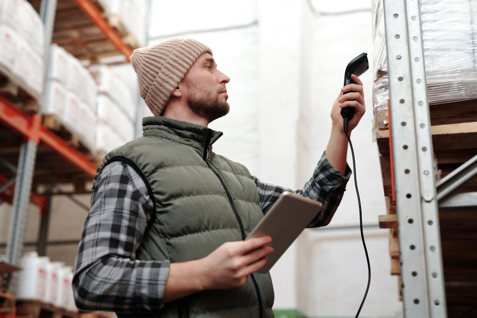 Warehouse worker scanning a shelved pallet with a handheld barcode scanner
