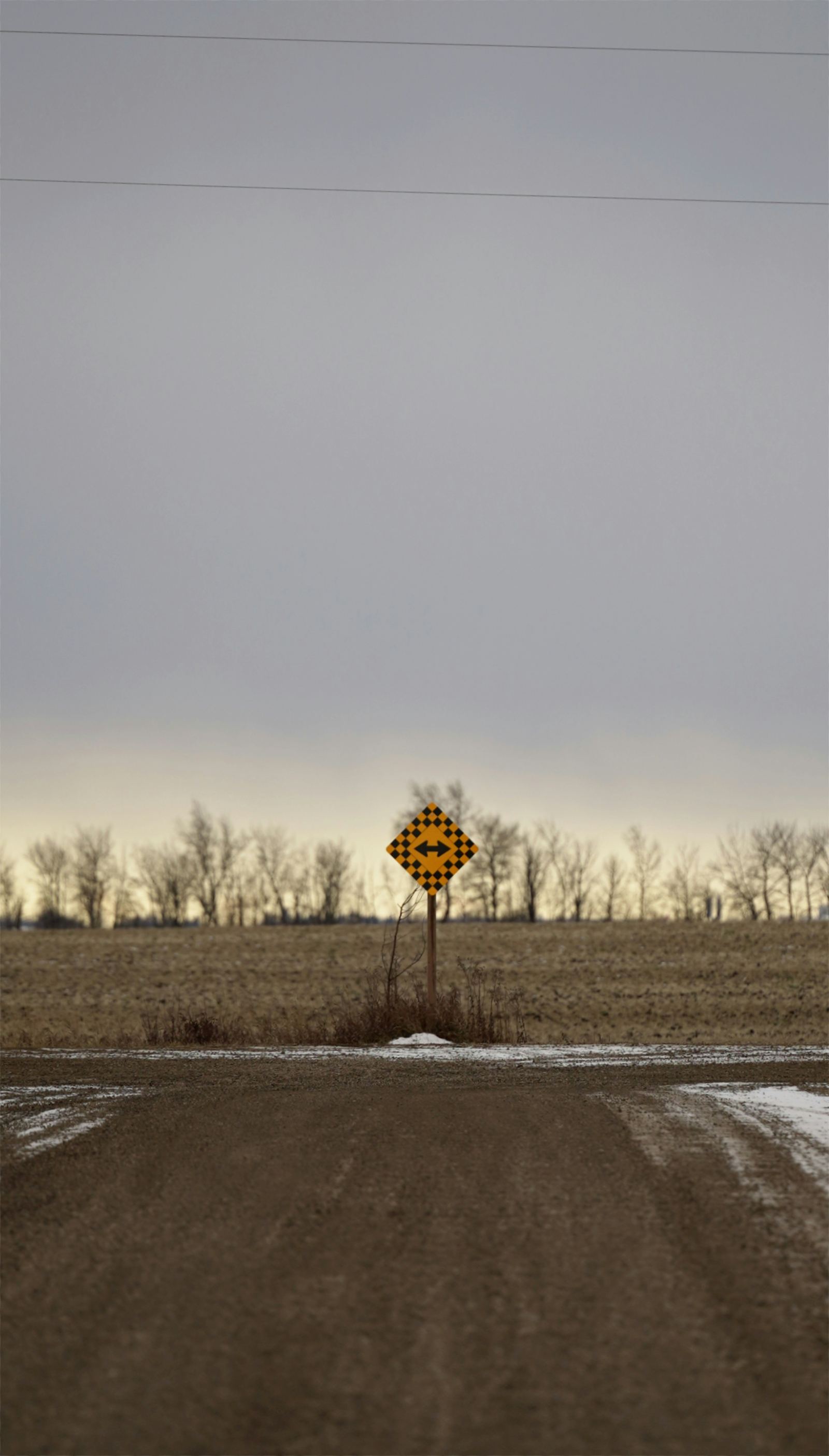 Yellow diamond-shaped directional road sign standing in an open field