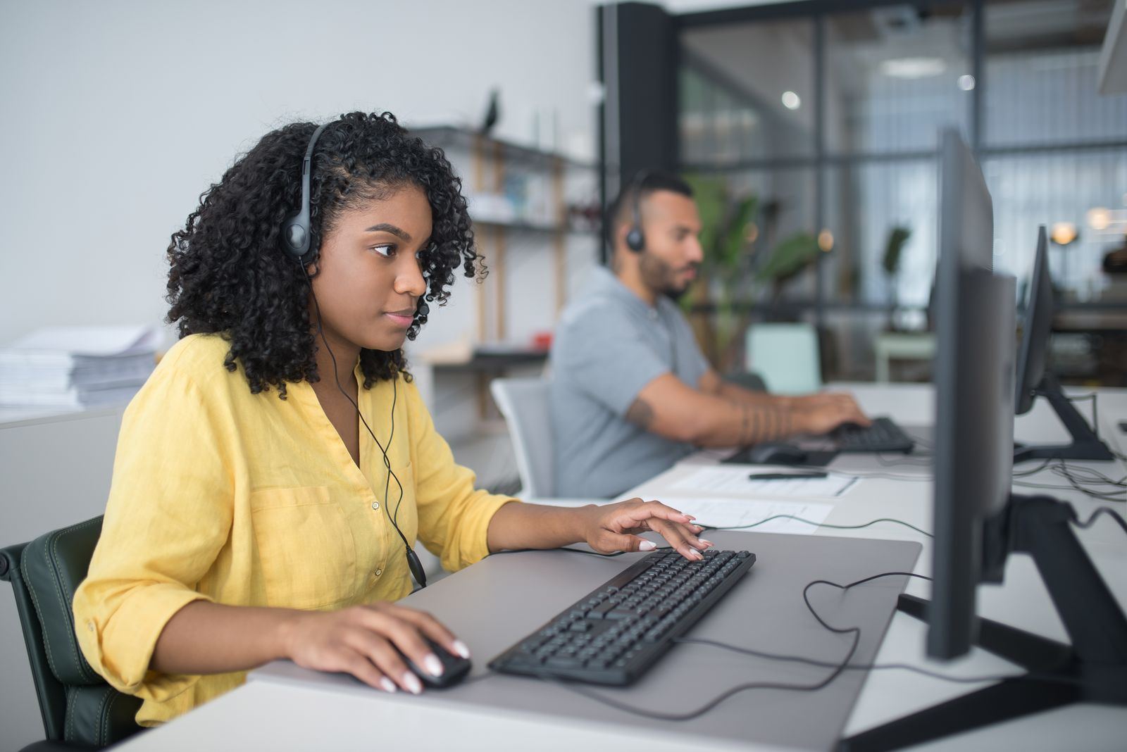 Customer support agent wearing a headset at a computer desk