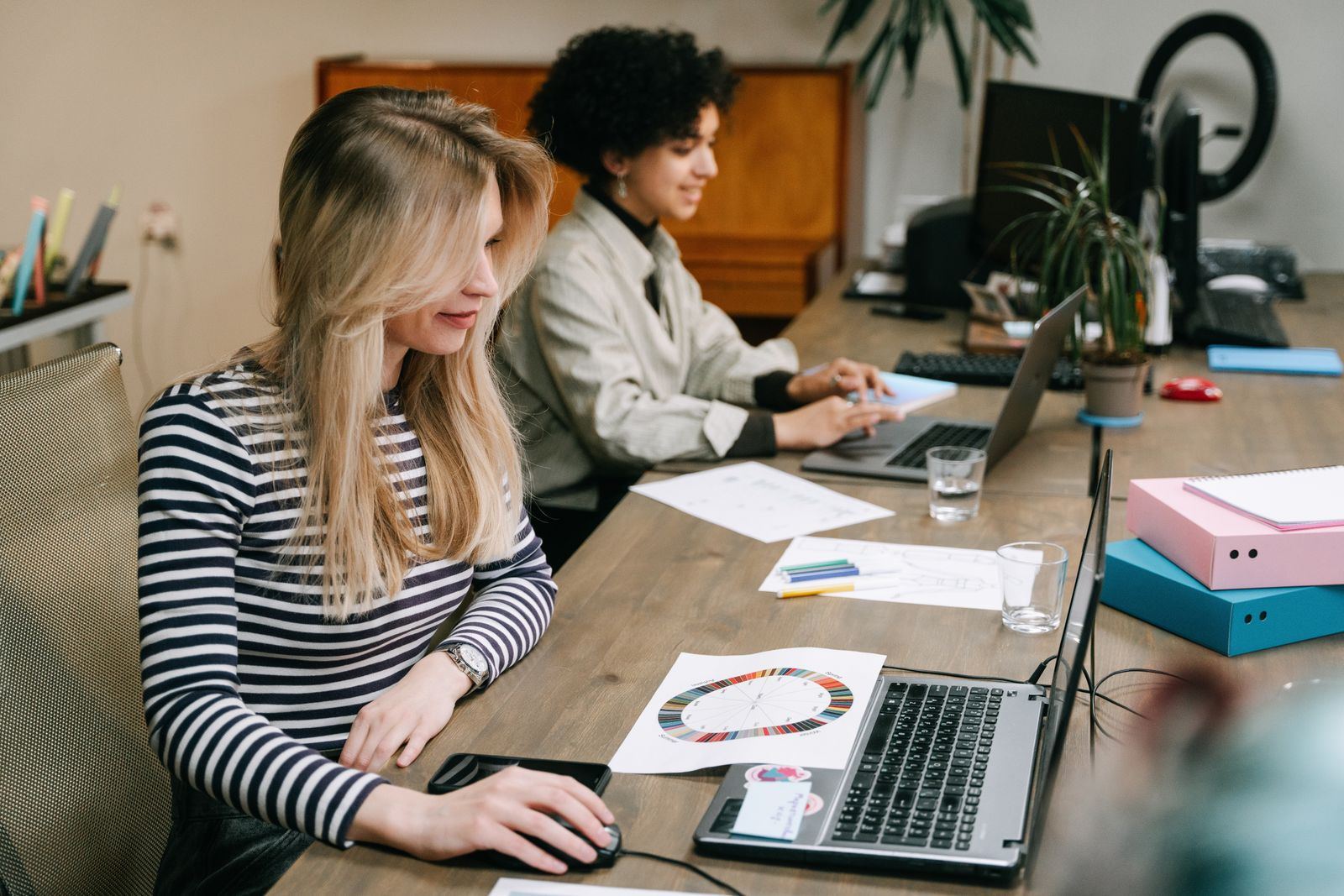Two colleagues collaborating together at laptops in an office