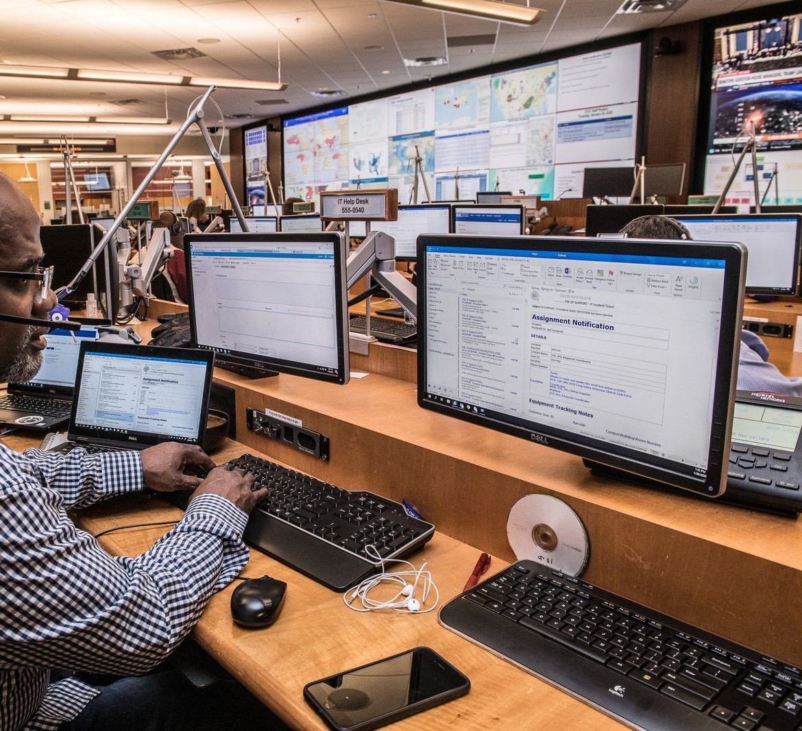 Dispatcher at a multi-monitor desk coordinating live jobs