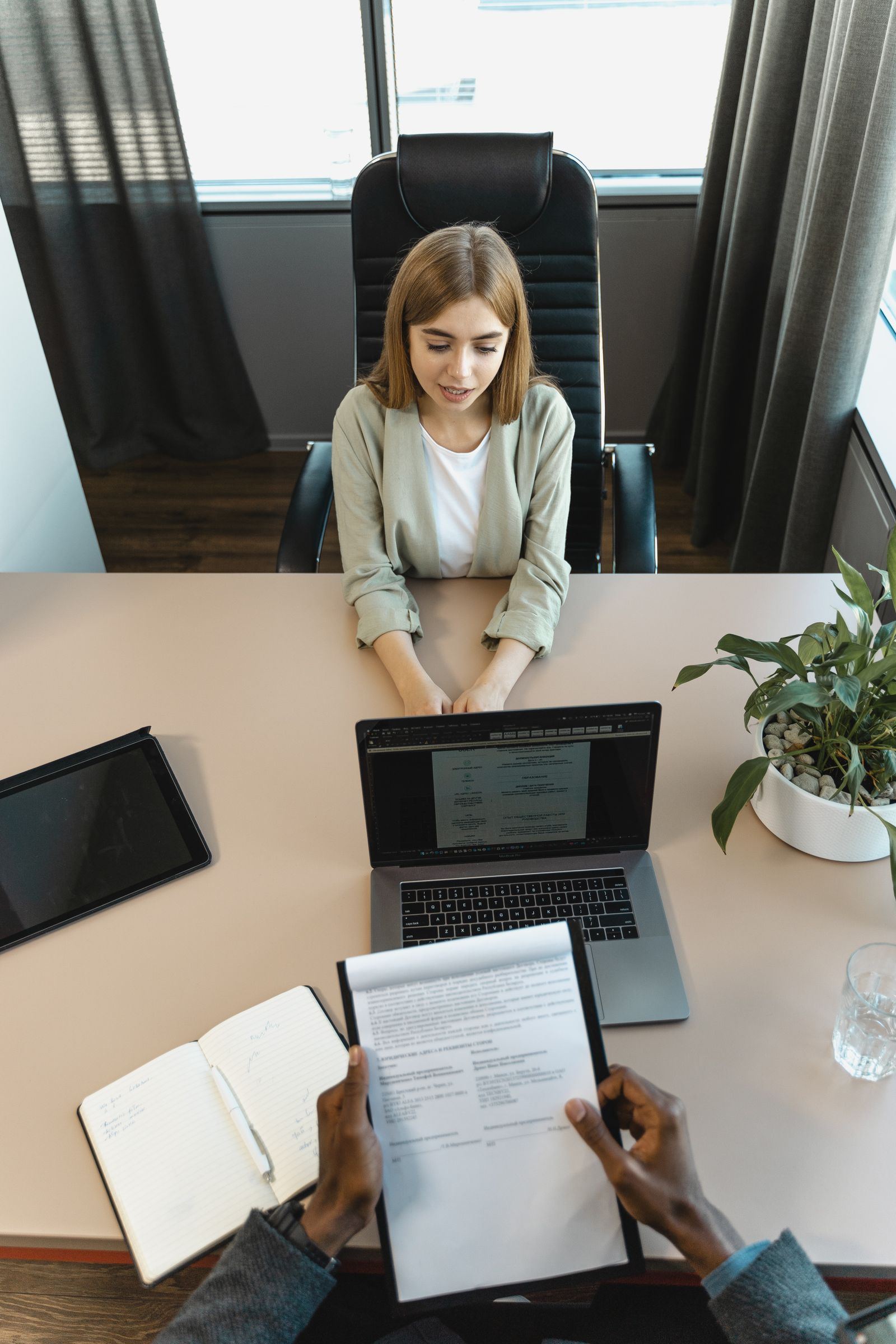 Overhead view of a job interview with a resume and laptop on the desk