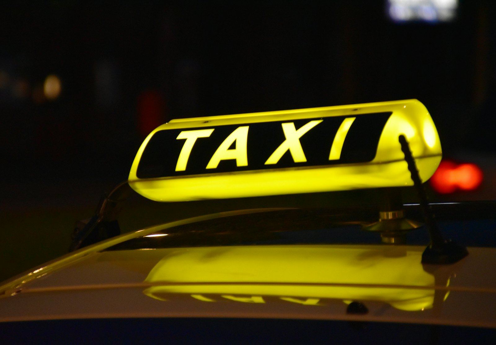 Illuminated taxi roof sign at night, representing 24/7 taxi dispatch and call answering coverage