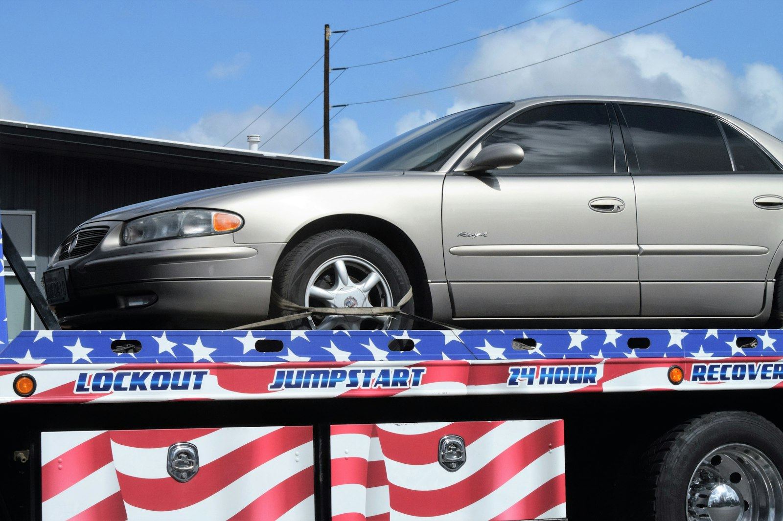 Flatbed tow truck offering lockout, jumpstart and 24 hour recovery service