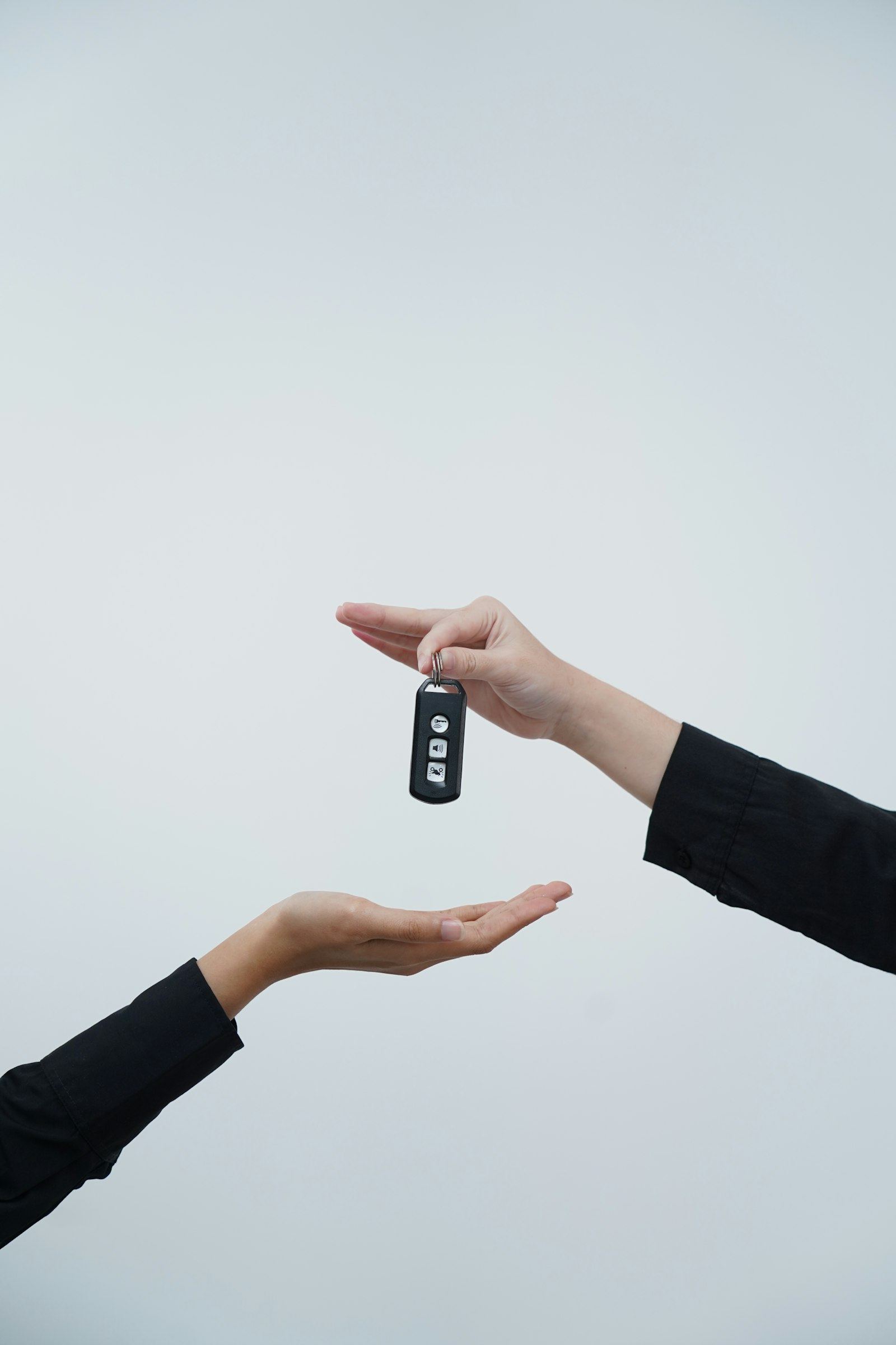 Close-up of a car key being handed from one person to another