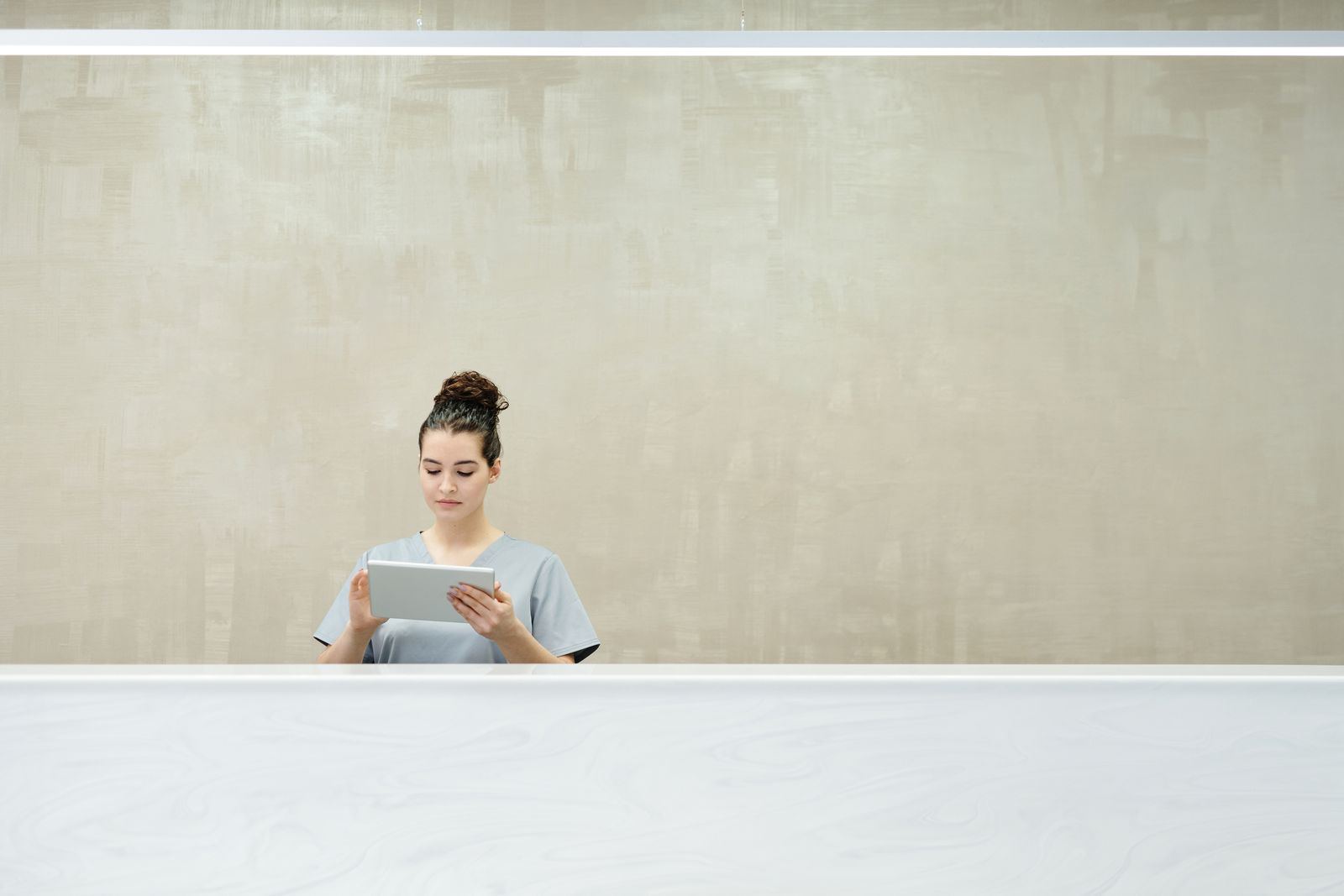 Receptionist behind a front desk counter holding a tablet